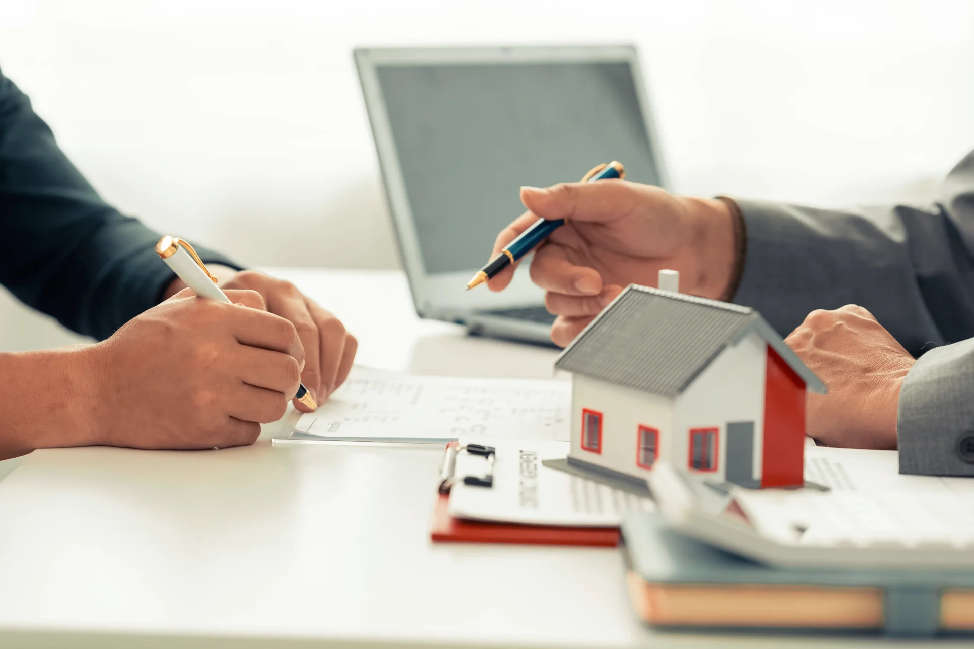 Two people signing real estate contract documents.