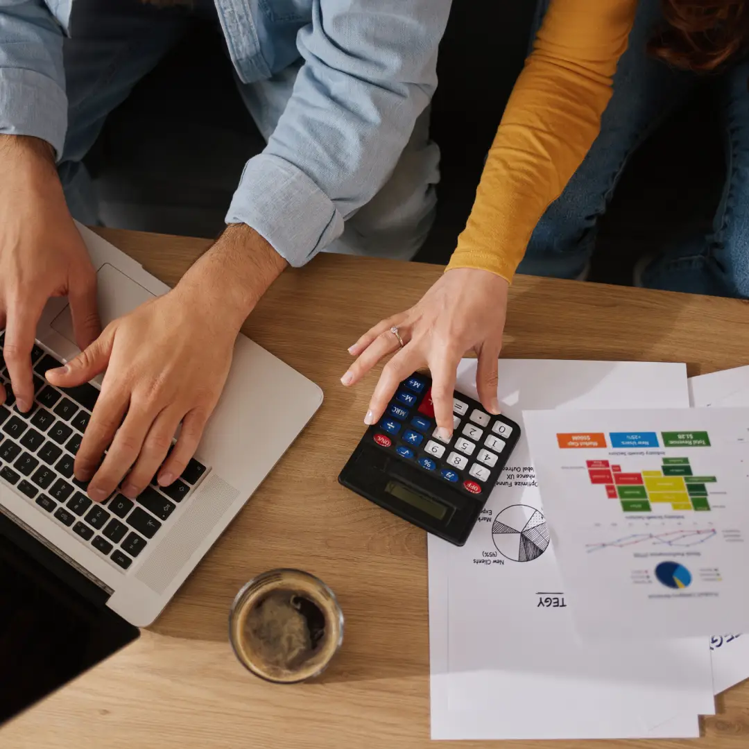 People working with laptop and calculator together.