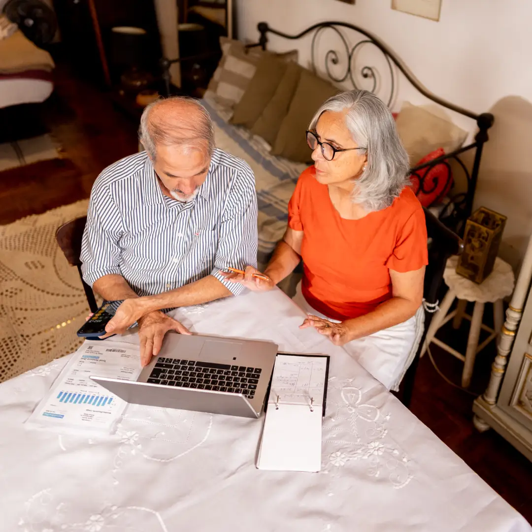 Older couple discussing finances on laptop.